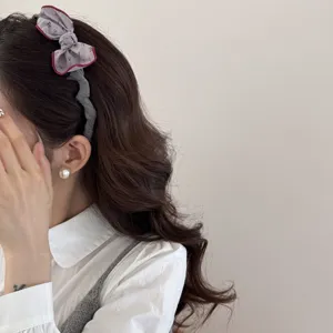 Close-up of vintage padded bow headband on brown wavy hair with pearl earring