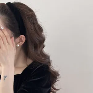 Close-up detail of an elegant black velvet twisted headband worn by a model on wavy hair