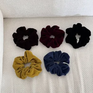 Detail macro view showing five colors of retro velvet scrunchies on textured fabric