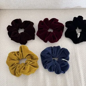 Five velvet hair scrunchies in autumn colors like burgundy, navy, and mustard yellow.