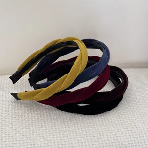 Detailed view of four braided velvet headbands in mustard, navy, burgundy, and black