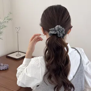Back view of a woman wearing a soft grey padded retro scrunchie in a low ponytail.