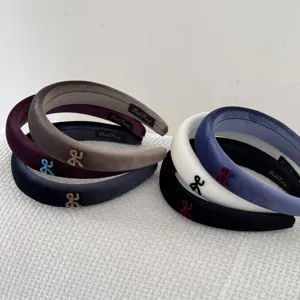 Close-up display of multiple colored velvet wide headbands featuring small bow accents.