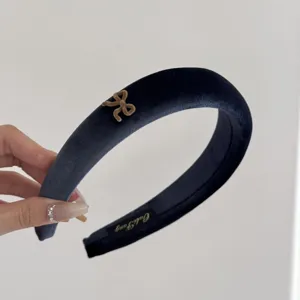 Detail view of a blue velvet padded headband with a small beige bow ornament.