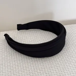 Détail rapproché d'un serre-tête large noir pour femme avec plis accordéon français