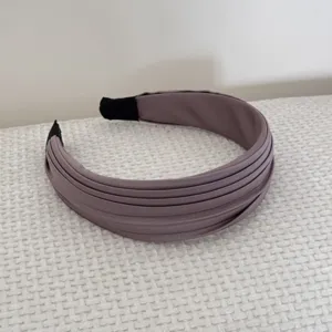 Détail montrant l'élégante texture satinée d'un serre-tête plissé mauve style français.