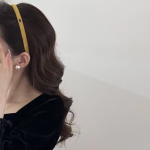 Detailed side view of a minimalist yellow suede thin headband worn on dark wavy hair