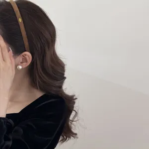 Detail view of minimalist brown suede thin headband with small gold plate on model hair