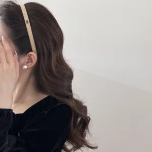 Macro detail of a slim tan suede headband worn on dark wavy hair for autumn styling