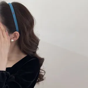 Detail view of a blue suede narrow headband featuring a small gold charm with Love text