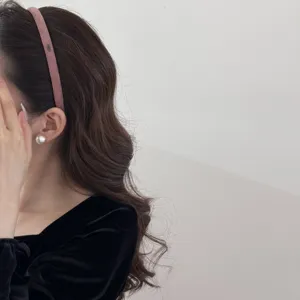 Close-up detail of a slim pink suede headband with small gold tag worn by a model