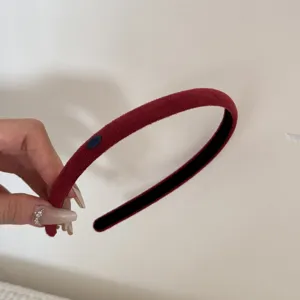 Detailed view of a thin burgundy faux suede headband with a small blue Love tag