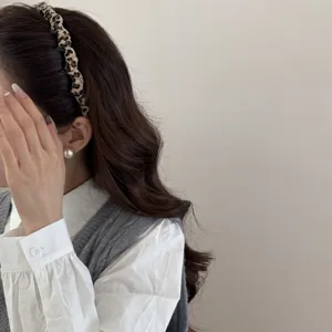 Primer plano de una diadema con estampado de leopardo en el pelo ondulado castaño de mujer