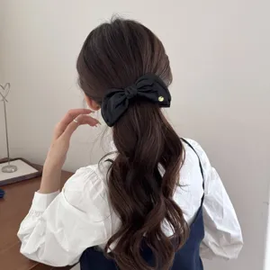 Detailed back view of a vintage black denim bow hair banana clip styling a wavy ponytail