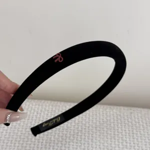 Detail view of a vintage black velvet slim headband featuring a small pink bow accent