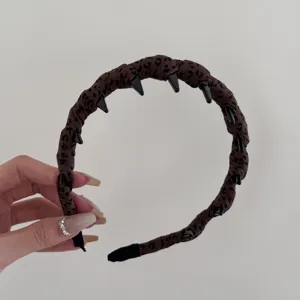 Detalle de diadema de tela con estampado de leopardo marrón y dientes negros antideslizantes