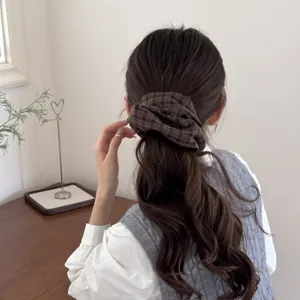 Macro view of a retro brown plaid scrunchie styled on a brunette low ponytail
