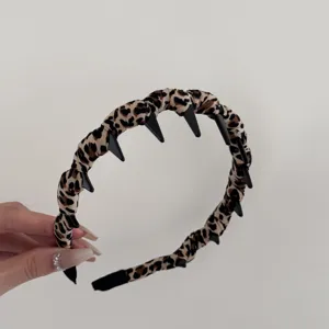 Primer plano de una diadema de tela con estampado de leopardo y dientes negros antideslizantes