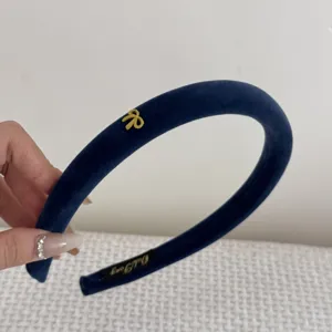 Detailed close-up of a navy blue velvet headband featuring a small gold bow charm