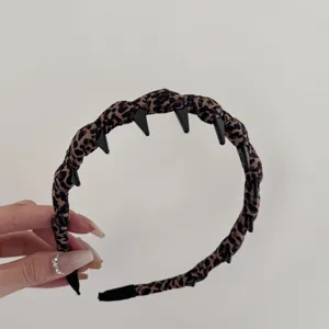 Detalle que muestra la diadema envuelta en tela de leopardo con dientes interiores negros