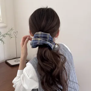 Close-up detail of a retro blue plaid scrunchie styled in a low ponytail hairstyle