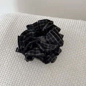 Vue détaillée d'un chouchou en tissu écossais vintage foncé avec une étiquette faite main.