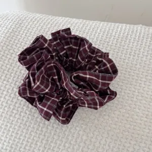 Gros plan d'un chouchou vintage en tissu écossais bordeaux avec motifs à carreaux blancs