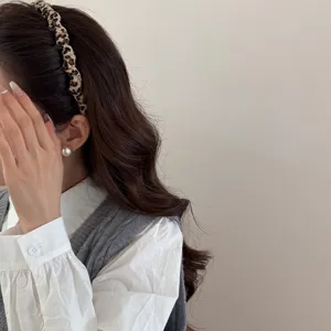 Modelo profesional con una diadema de tela con estampado de leopardo y fondo neutro