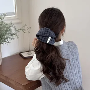 Close-up of a dark checkered fabric scrunchie worn in a low ponytail