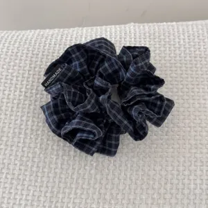 Vue rapprochée d'un chouchou en tissu à carreaux bleu marine et noir avec une étiquette faite main