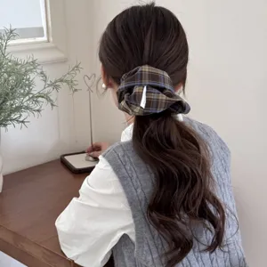 Back view of a model styling a dark plaid retro scrunchie in a neat low ponytail.