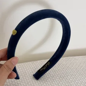 Gros plan d'un serre-tête rembourré en velours bleu marine avec un petit cœur jaune.