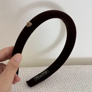 Vue détaillée d'un serre-tête en velours marron avec décor de cœur et étiquette de marque dorée