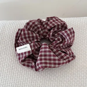 Detailed macro view of a burgundy checkered retro fabric scrunchie with hand made tag