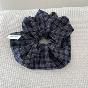 Macro view of a dark blue vintage plaid scrunchie with a handmade label tag