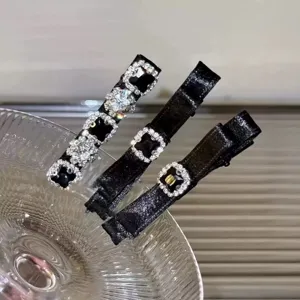 Close-up of elegant black satin hair clips embellished with glittering square rhinestones