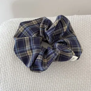 Detail view of retro plaid fabric scrunchie with handmade tag for elegant hair styles.