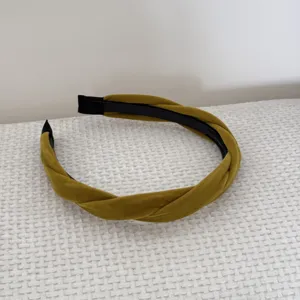 Detailed close-up view of a mustard yellow twisted velvet headband with soft texture.