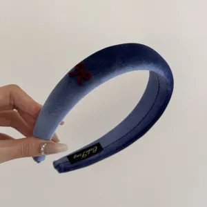 Close-up of elegant blue velvet wide headband with a delicate red bow detail.