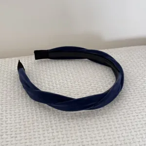 Close-up view of a dark blue braided velvet headband with elegant soft fabric texture.