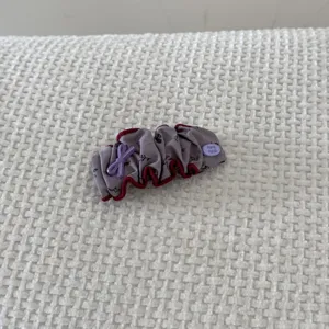 Detail view of a vintage padded grey scrunchie hair clip with a handmade button