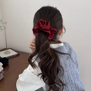 Gros plan d'un chouchou plissé rouge à double couche élégant sur une queue de cheval.