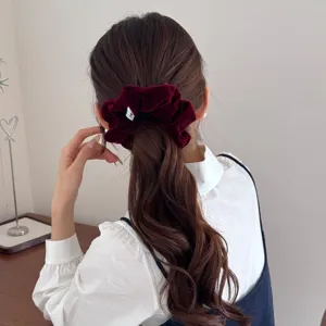 Elegant burgundy velvet scrunchie on a wavy low ponytail for a retro autumn look.