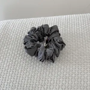 Detailed view of the soft pleated texture on a vintage grey cotton-filled hair scrunchie