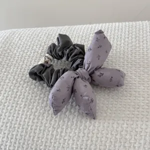Detailed view of a vintage floral stuffed bow scrunchie on white textured fabric