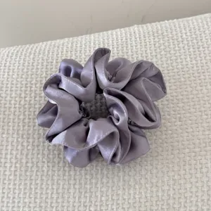 Détail d'un chouchou en satin violet de luxe à double couche avec des volants.
