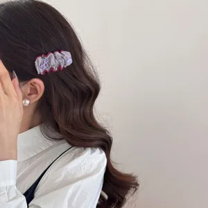 Elegant vintage cotton-filled hair clip with red ruffled edges shown on model's hair