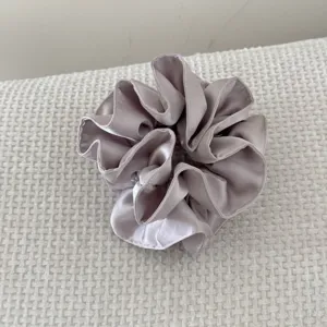 Détail d'un chouchou en satin gris à double couche avec plis et volants élégants