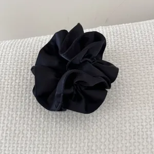 Détail d'un chouchou en satin noir à double épaisseur avec une texture de tissu élégante