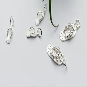 Close-up of S925 silver flip-flop charms with intricate floral and textured patterns